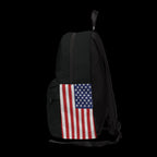 A black backpack shown from the back, featuring a distressed American flag print on the lower back panel, photographed against a solid white background.