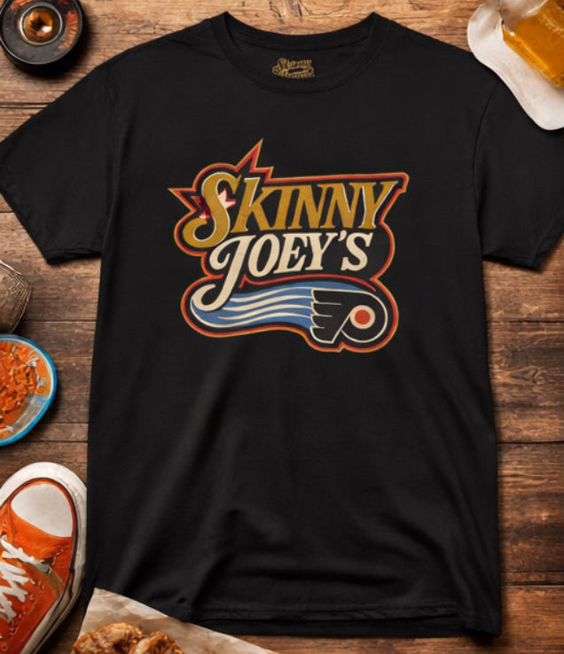 Black t-shirt with 'Skinny Joey's' logo on a wooden surface with snacks and drinks.