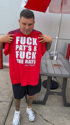 Lil Snuff holding a red t-shirt with white text outdoors.
