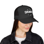 Person wearing a black cap with 'Skinny' text on a white background