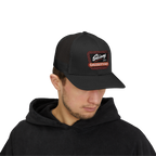 Person wearing a black cap with a logo on a white background