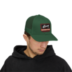 Person wearing a green cap with a patch on a white background