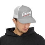 Person wearing a gray and white cap with 'Skinny Joey's' logo on a white background