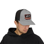 Person wearing a gray and black cap with a logo on a white background