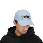 Person wearing a light blue cap with 'The Skinny' logo on a white background