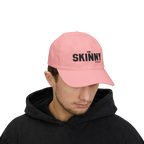 Person wearing a light blue cap with 'The Skinny' logo on a white background