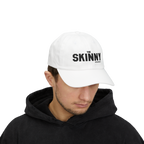 Person wearing a light blue cap with 'The Skinny' logo on a white background