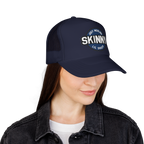 Person wearing a navy blue cap with 'SKINNY' logo on a white background