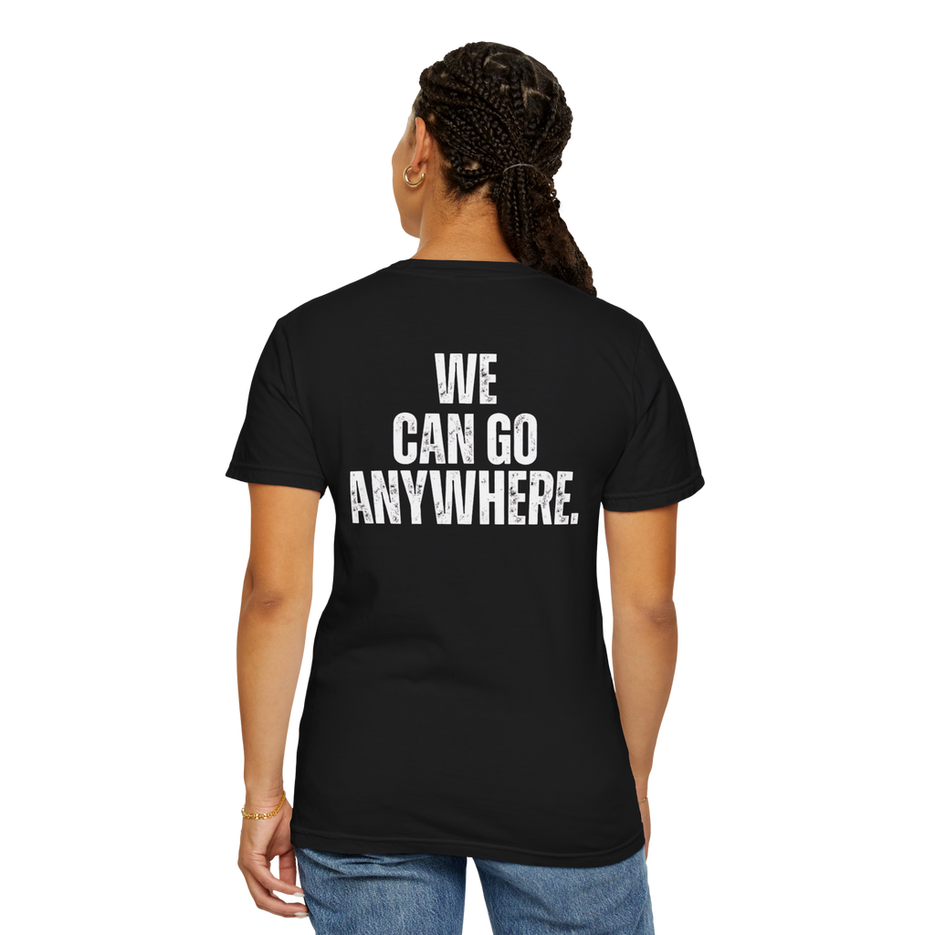 Person wearing a black t-shirt with 'WE CAN GO ANYWHERE.' text on the back, standing against a white background.