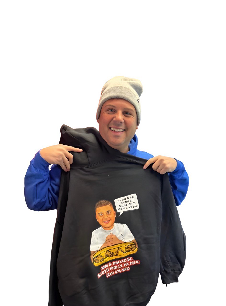 Person holding a black hoodie with a graphic design on a white background